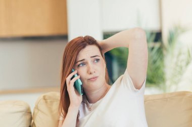 Genç ve güzel bir kadın evde, kanepede tek başına oturuyor, acı ve depresyon hissediyor telefonda bir arkadaşına şikayet ediyor.