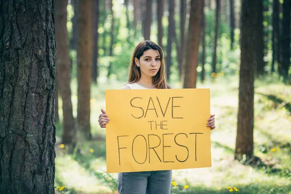 森の中で美しい女性ボランティア活動家がポスターで森を救う — ストック写真