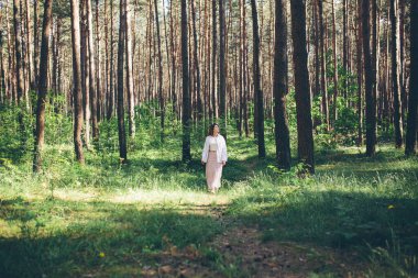 Genç ve güzel hippi kadın yaz ormanında yürüyor gülüyor, dans ediyor ve hayatın ve doğanın tadını çıkarıyor.
