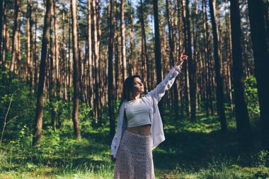 Genç ve güzel hippi kadın yaz ormanında yürüyor gülüyor, dans ediyor ve hayatın ve doğanın tadını çıkarıyor.