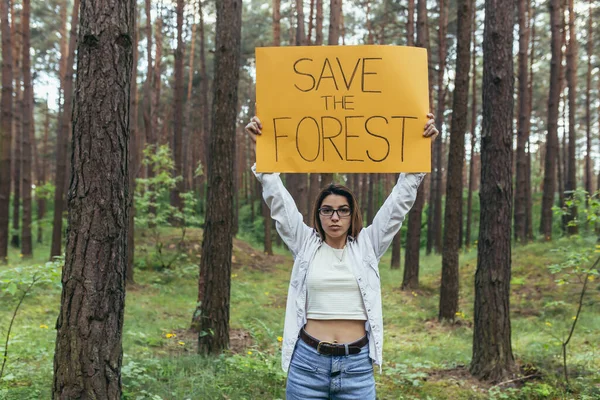 森でボランティアをしている若い女性が森を救うポスターを持っています — ストック写真