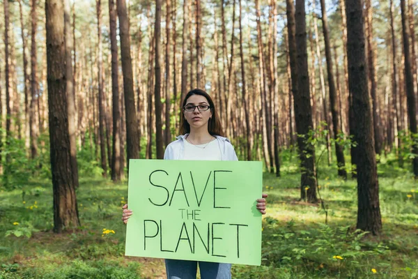 森の中にポスターを貼った若い女性活動家が地球を救うボランティアが森林破壊と闘っている — ストック写真