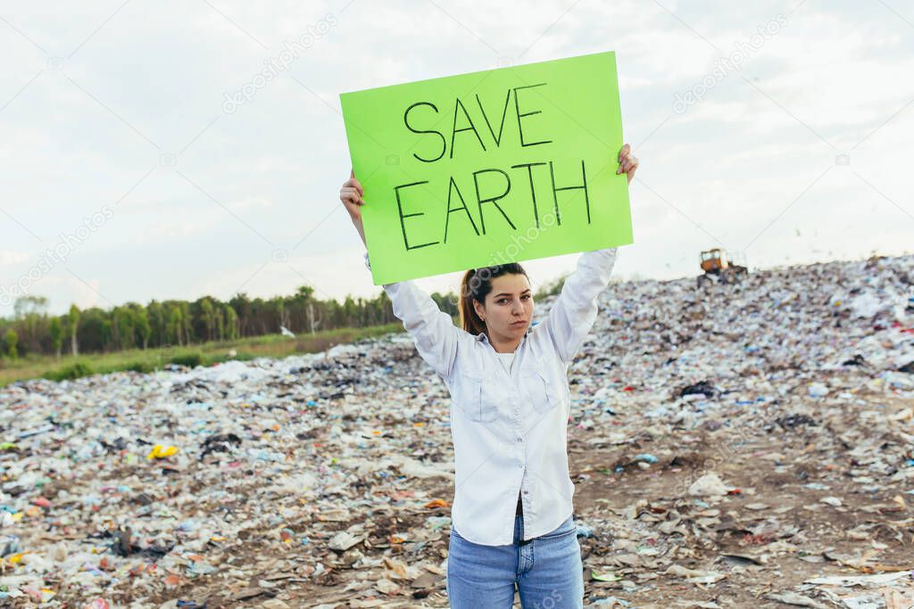 Woman at landfill volunteer holding a poster save the earth