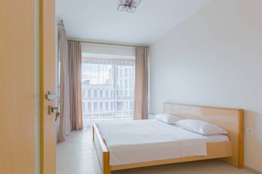 Bir yatak odasının içinde açık renkli büyük bir yatak odası.