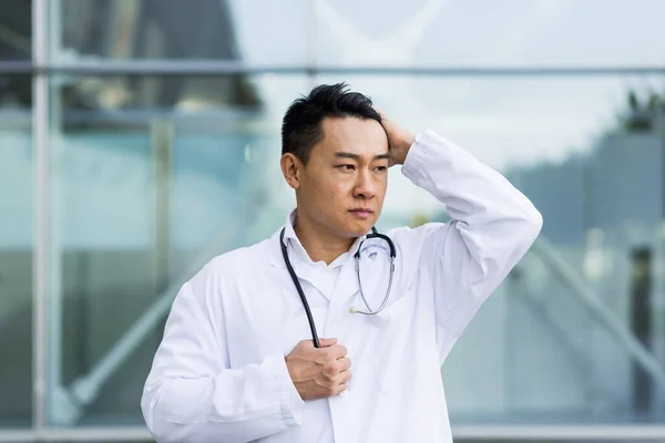 Asian doctor is tired after work, depressed and disappointed with the work done on the street near the clinic