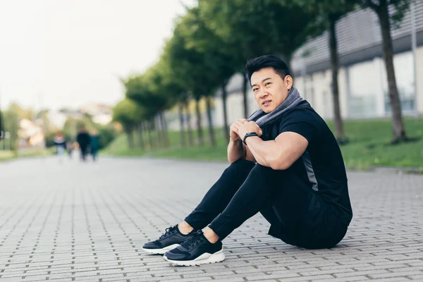 asian man after fitness workout and jogging sitting on the ground tired resting