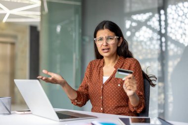 Woman feeling frustrated and confused while attempting an online payment with a credit card on her laptop, encountering a problem with the transaction