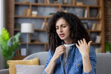 Sıcak ve terli bir kanepede acı çeken bir kadın, bunaltıcı bir oturma odasında ateş ya da sıcak bir ışık altında, kendini kötü hisseden, bitkin ve susuz hisseden bir kadın.