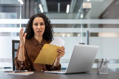 Masasındaki kahverengi zarftan gelen kritik bir belgeyi açtıktan sonra genç profesyonel bir kadın üzgün ve kafası karışık hissediyor. İş gününün zor bir döneminde beklenmedik bir bilgiyi işliyor.