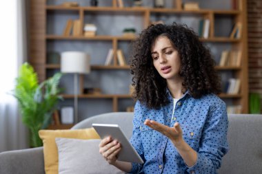 Hayal kırıklığına uğramış yüz ifadesi olan bir kadın çevrimiçi bir video konferansında sorun yaşıyor, kötü haber alıyor veya gönderiyor veya dijital tablet kullanarak evden sorunları tartışıyor.