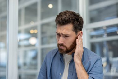 Kulağına tutunan, kulak ağrısı, kulak çınlaması ya da işitme sorunu olan bir adam, tedavi gerektiren bir sağlık sorununu işaret ediyor.