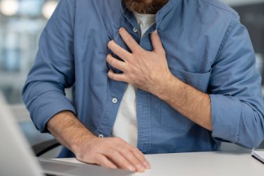 Ofis masasında göğsünü sıkan bir adam ani akut göğüs ağrısı kalp krizi ya da acil tıbbi kriz ve rahatsızlıktan dolayı ağır kalp krizi geçirmiş.