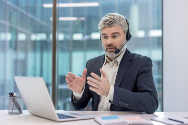 İş adamı sanal bir toplantı yapıyor, modern bir ofisten uzaktan çalışırken müşterilerle veya iş arkadaşlarıyla iletişim kuruyor, destek veriyor ve aktif olarak tartışıyor.