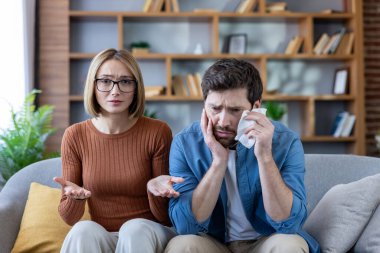 Bir psikoloğa danışarak evliliklerinin ve aile içi çatışmaların çözümünü tartışan üzgün koca ve stresli eş..