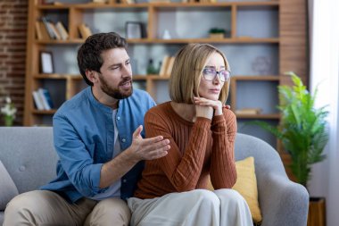 Kadın sırtını dönüp giderken, erkek üzgün bir eşe uzanıyor oturma odasındaki anlaşmazlık üzerine gergin bir çift, duygusal bir özür anı, destek ve uzlaşma çabası.