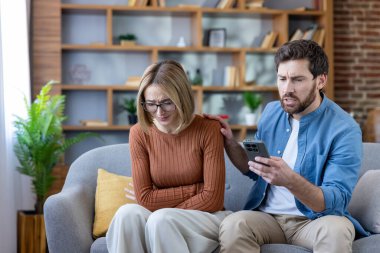 Genç adam acil tıbbi yardım için akıllı telefon kullanıyor ve evde şiddetli mide ağrısından muzdarip ortağını rahatlatıyor, online sağlık hizmeti ya da ambulans arıyor..