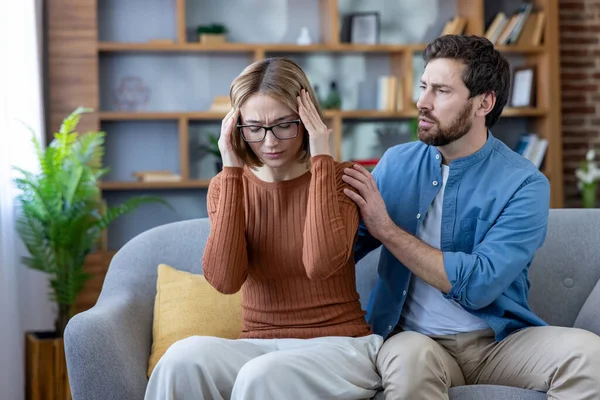 Partnerleri kanepeye yakın oturup destek verirken kadınlar şakaklarına sıkı sıkı tutunuyor. Gergin bir çift evde stres ve duygusal acıyla boğuşuyor.