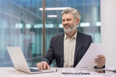 Üst düzey profesyonel erkek aktif olarak teknoloji ve evrak işleriyle uğraşıyor, iş geliştirme, finans ve başarılı şirket stratejisini temsil ediyor.