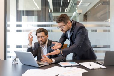 Modern bir ofiste iki stresli iş adamı, biri katı bir patrondan endişe ve baskı görüyor, işyerindeki anlaşmazlık ve işyerinde algılanan bir hata ile uğraşıyor.