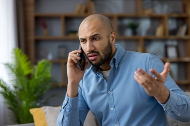 Cep telefonuyla konuşan genç adam, evde gergin bir konuşma sırasında stres, endişe ve hayal kırıklığı gösteren kötü haberler alıyor, çatışma ve hayal kırıklıklarını iletiyor.