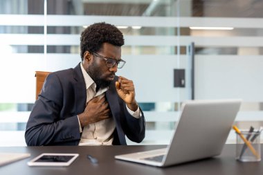 Modern bir ofiste masasında oturan Afrikalı Amerikalı işadamı kendini kötü hissediyor ve yumruğuna öksürüyor. Çalışırken göğsünde ağrı ve rahatsızlık hissediyor.