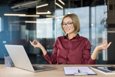İş kadını ofis masasında sükunet ve sükunet buluyor, yoğun bir iş gününde meditasyon ve farkındalık yapıyor, stresi azaltıyor ve zihinsel sağlığı destekliyor.
