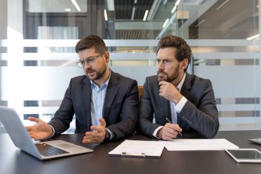 Modern ofiste yapılan profesyonel toplantılarda dizüstü bilgisayardaki verileri analiz eden ve önemli iş bilgilerini tartışan işadamları, büyüme için çözümler buluyorlar