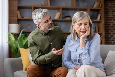 Olgun bir adam üzgün karısını bir kanepede oturup teselli ederken, ilişki sorunları ve üzüntü ile ilgilenirken destek ve empati gösteriyor.
