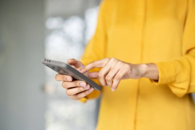 Cep telefonu tutan, dokunmatik ekranla etkileşim halinde olan, içeriği taramak için yazı yazan ve kaydıran, bağlı kalan ve günlük görevler ve sosyal medya için teknolojiyi kullanan kişi