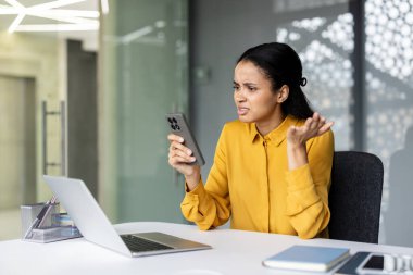 Mutsuz iş kadını cep telefonunu kontrol ediyor. Sinir bozucu ve stresli bir mesaj, teknik sorunlar ya da modern bir ofisteki zor bir iş sorunu yüzünden.