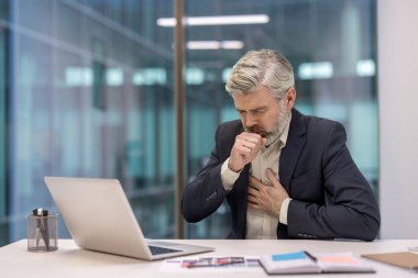 Yetişkin bir işadamı, bilgisayarının başında çalışırken acı verici bir öksürük ve göğüs rahatsızlığı yaşıyor.