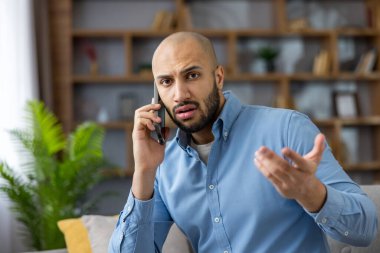 Genç kel bir adam telefon ediyor, iletişim sorunları yaşıyor ve ev ofisinden telgraf çekerken hayal kırıklığını veya yanlış anlaşılmaları dile getiriyor.
