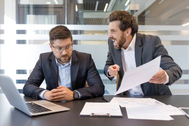 Erkek yönetici yoğun bir masada ezilmiş bir astını azarlıyor, işyerindeki çatışmaları, stresi, zorbalıkları ve gergin, zehirli bir ofis çatışmasını yakalıyor.