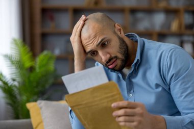 Genç adam evde oturup bir zarftan gelen mektubu okuyor. Beklenmedik faturalar, borç veya kötü haberler karşısında endişe ve umutsuzlukla tepki veriyor. Bunalmış ve dalgın.