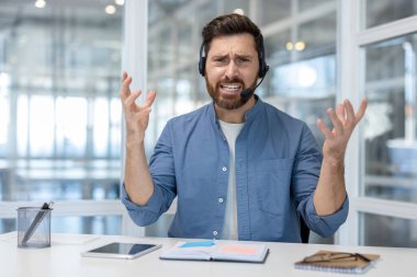 Kulaklık takan ve hayal kırıklığına uğramış bir çağrı merkezi ajanı müşteriye sorunları ve kötü hizmet tecrübesi olan çevrimiçi teknik destek hizmeti sunuyor.