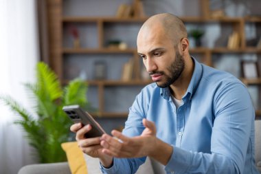 Akıllı telefonunu kullanmaya çalışan bir adam, karmaşık veya arızalı bir cep telefonuyla sinir bozucu bir teknolojiye sahip.