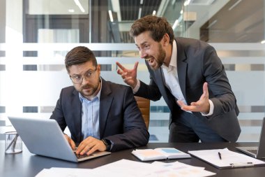 Kızgın patron bir ofis ortamında stresli bir çalışana bağırıyor, zehirli bir çalışma ortamı yaratıyor ve çatışma, baskı ve kötü yönetim tasvir ediyor.