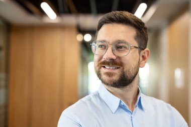 Profesyonel iş adamı, sakallı, gülümseyen, kapalı ofis ortamında güven içinde poz veren, başarıyı, başarıyı ve şirket liderliğini temsil eden,