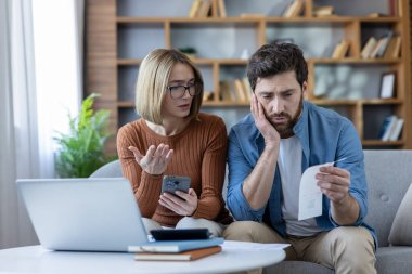 Finansal sorunlar ve borçla karşı karşıya olan endişeli çift, aile bütçesini dizüstü bilgisayar ve telefonla hesaplıyor, artan harcamalar ve ekonomik krizle ilgili endişelerini dile getiriyor