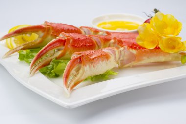 Haşlama yengeç pençeleri sos ve beyaz arka plan üzerinde bir tabakta limon ile