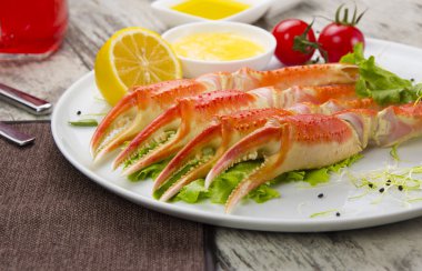 Haşlama yengeç pençeleri sos ve beyaz arka plan üzerinde bir tabakta limon ile