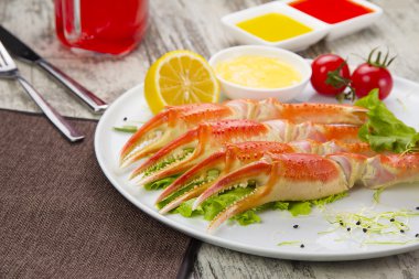 Haşlama yengeç pençeleri sos ve beyaz arka plan üzerinde bir tabakta limon ile