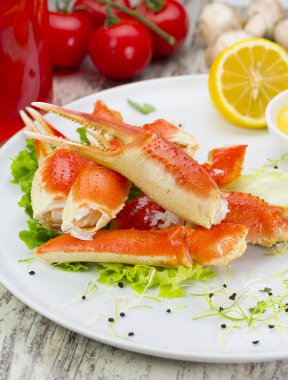 Haşlama yengeç pençeleri ahşap arka plan üzerine sosunu, limon ve kiraz domates ile