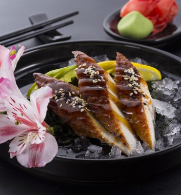 Yılan balığı sashimi buzlu zencefil wasabi siyah arka plan üzerinde siyah bir plaka üzerinde