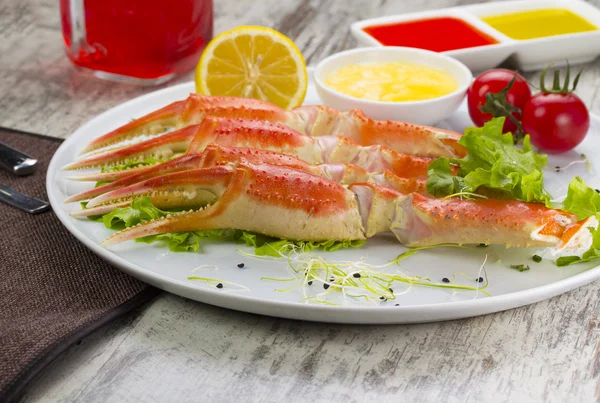 Garras de cangrejo hervidas con salsa, limón y tomate cherry con sabrosa bebida sobre fondo de madera — Foto de Stock