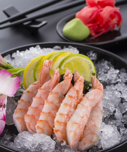 Cozinha japonesa, camarão Sashimi com gelo com gengibre e wasabi em um prato preto — Fotografia de Stock