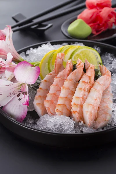 Cucina giapponese, gamberetti Sashimi con ghiaccio con zenzero e wasabi su un piatto nero — Foto Stock