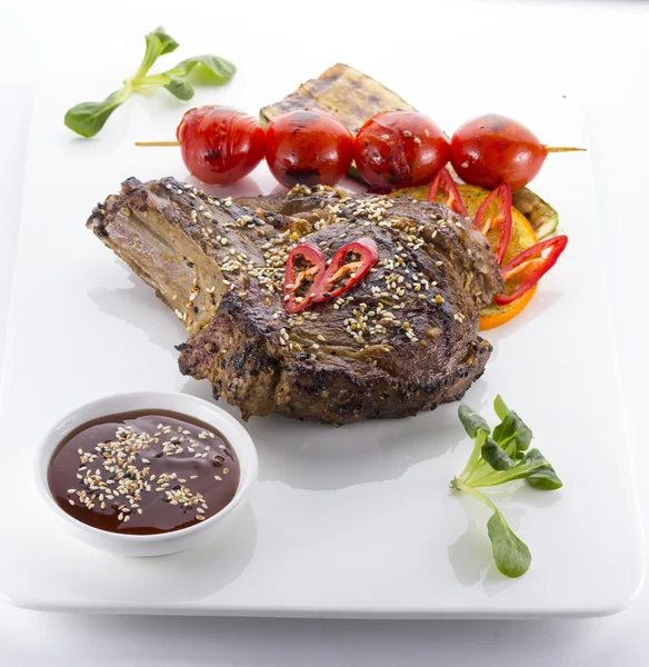 Steak de bœuf servi avec tomates et sésame dans une assiette blanche — Photo