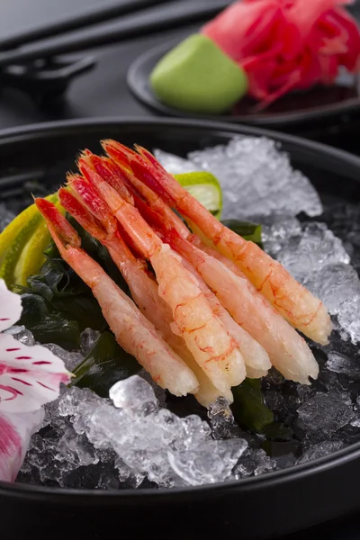 Japanische Küche, Shrimp Sashimi mit Eis mit Ingwer und Wasabi auf einem schwarzen Teller — Stockfoto