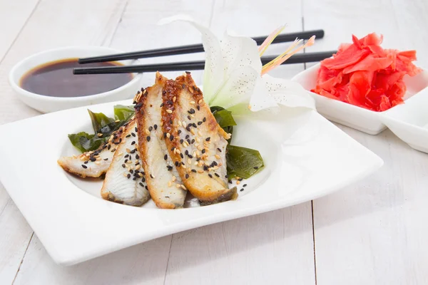 Paling sashimi met sojasaus op een witte plaat over houten achtergrond — Stockfoto